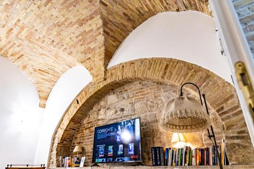 a library with a brick wall and a chandelier at La Rua in Ascoli Piceno