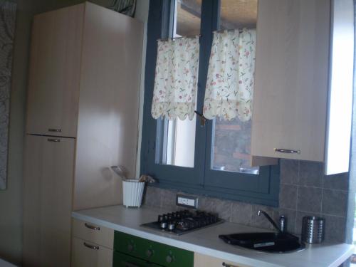 a kitchen with a stove and a window with curtains at Il Giardino Di Emilio in Marrùbiu