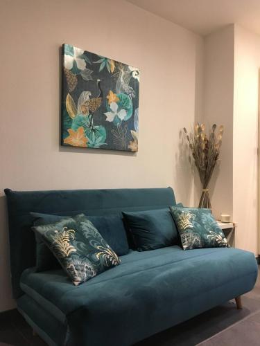 a blue couch in a living room with a painting at Gîtes De La Bonne Etoile in Geispolsheim