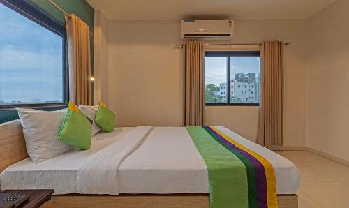 a bedroom with a large bed with two windows at Treebo Tulip Comfort in Pune