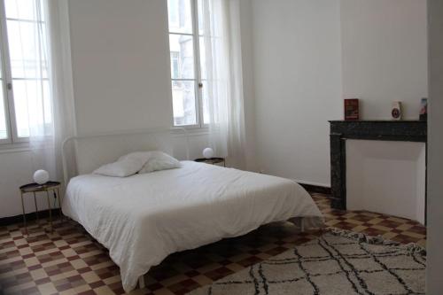une chambre blanche avec un lit et une cheminée dans l'établissement Noailles experience - Centre Marseille /Vieux-Port, à Marseille