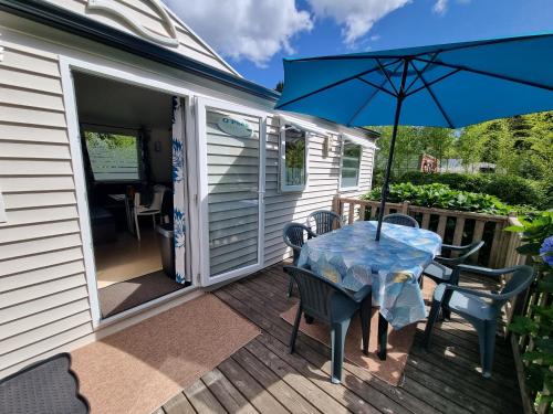 eine Terrasse mit einem Tisch, Stühlen und einem Sonnenschirm in der Unterkunft Camping de l Orangerie de Lanniron Mobilhome Esprit Zen R26 in Quimper