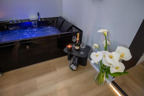 una bañera de hidromasaje con un jarrón de flores y una mesa con bebidas en Contemporaneamente 147 - Modern & Comfort Rooms, en Bari