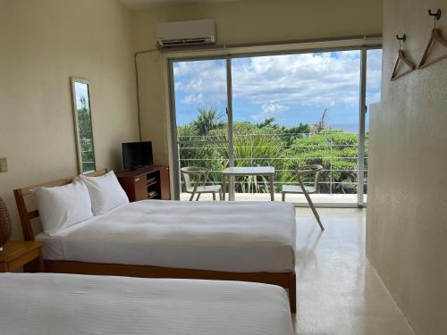 1 dormitorio con 2 camas y balcón con vistas. en 青の洞窟 'Blue in Green' 青の洞窟が目の前のコテージ! Ocean view & 満天の星! 広々セミダブルベッド, en Ishigaki Island