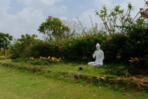 a statue of a person sitting in the grass at SaffronStays Sanvina Farm, Karjat in Karjat