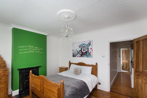 a bedroom with a bed and a green wall at Warm and Spacious Smart Stay - Close to Harry Potter World and mainline station connecting to London and Luton Airport - Contractors and corporate bookings welcome in St. Albans