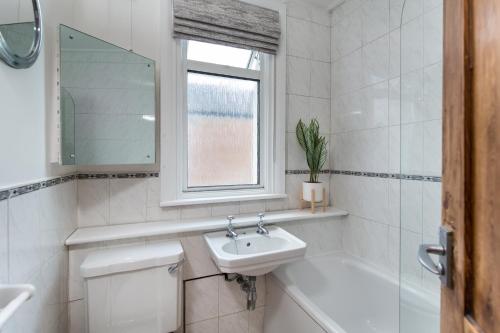 a white bathroom with a sink and a bath tub at Warm and Spacious Smart Stay - Close to Harry Potter World and mainline station connecting to London and Luton Airport - Contractors and corporate bookings welcome in St. Albans