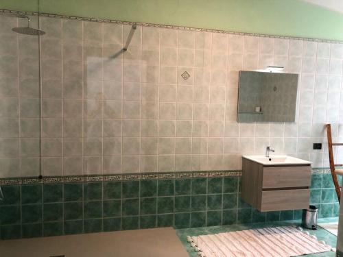 uma casa de banho em azulejo com um lavatório e um espelho. em Casa in centro Domodossola self check in em Domodossola