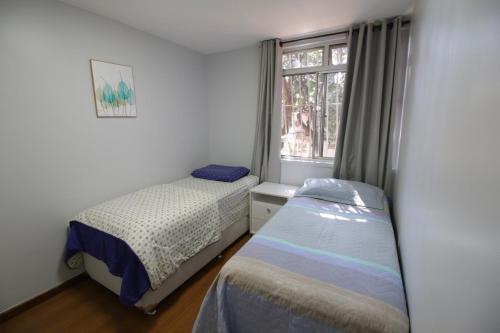 a bedroom with two beds next to a window at Apartamento ASA SUL in Brasília