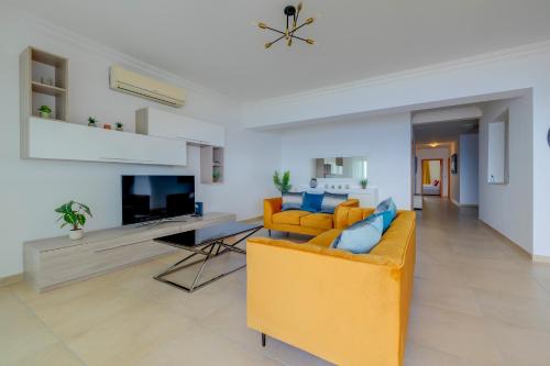 a living room with a yellow couch and a tv at Seafront Apartment Sliema in Sliema