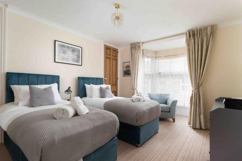 a bedroom with two beds and a chair and a window at Room 2, Hotel style twin bedroom in Marazion in Marazion