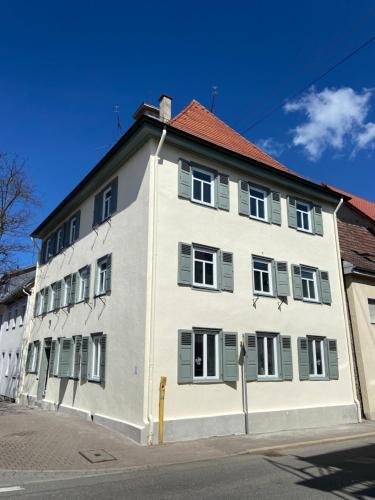 a white building with green shutters on a street at Hostel Balingen in Balingen