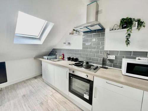 cocina blanca con fregadero y microondas en Exec 1-Bedroom Studio Apartment Briton Ferry, Neath Port Talbot 5, en Briton Ferry