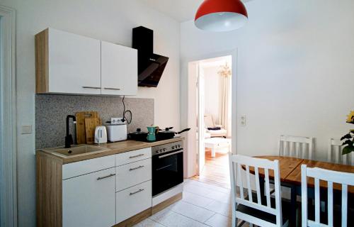 a kitchen with white cabinets and a wooden table with a counter at Die Jute Stube in Bad Freienwalde