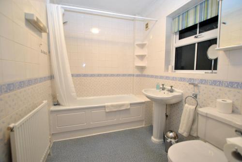a bathroom with a sink and a tub and a toilet at Garfield Place Cosy 2-Bedroom Cottage Central Windsor with Parking in Windsor