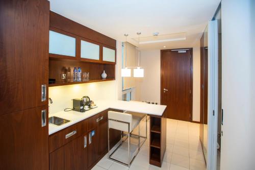 a kitchen with wooden cabinets and a white counter top at Centro Olaya by Rotana in Riyadh