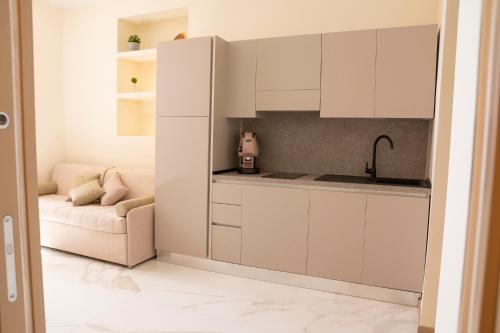 una cocina con armarios blancos y un sofá en una habitación en BelMa' Aparthotel and Rooms en Marina di Camerota