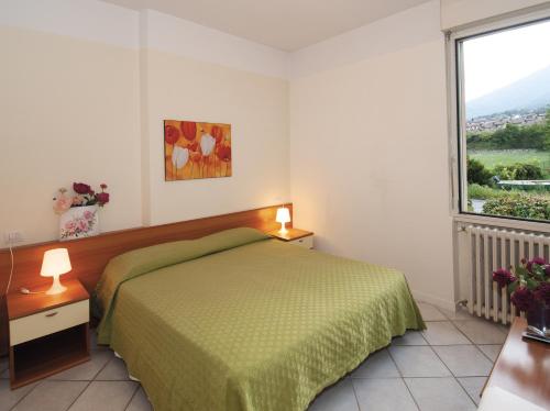 a bedroom with a green bed and a large window at Green Village Accommodations in Colico