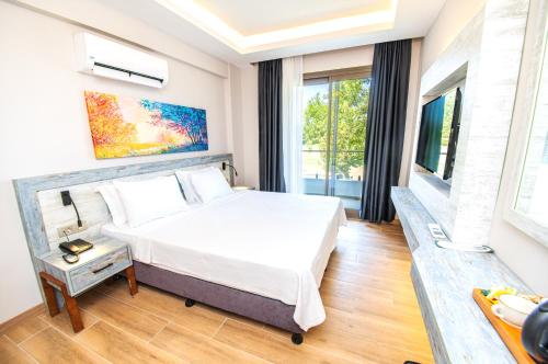 a bedroom with a bed and a large window at Feri Surf Club Hotel Datça in Datca