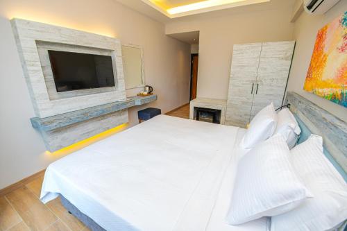 a bedroom with a white bed and a flat screen tv at Feri Surf Club Hotel Datça in Datca