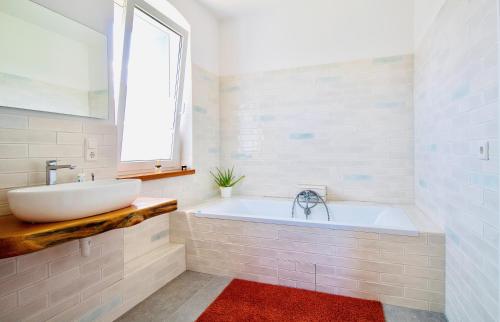 baño con bañera, lavabo y ventana en Das Atelier, en Bad Freienwalde