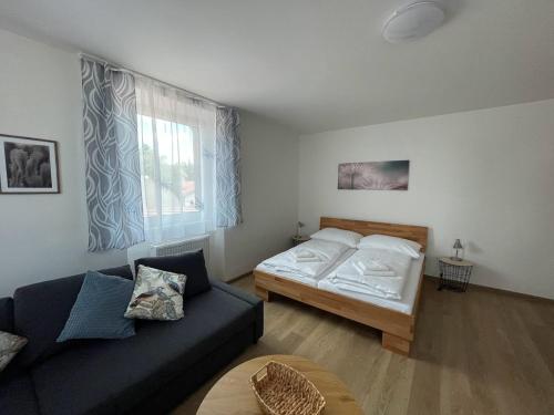 uma sala de estar com uma cama e um sofá em Apartmány Šumavánek em Zdíkov