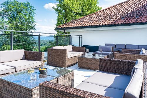 a patio with wicker furniture and a glass table at Robenstein Hotel & SPA - Villa in Zwiesel