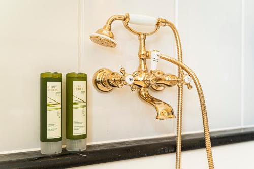 a brass shower head and two bottles on a sink at Robenstein Hotel & SPA - Villa in Zwiesel