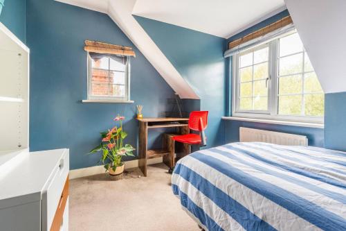 een blauwe slaapkamer met een bed en een bureau bij Room in Guest room - Calm For 3, Handy For Airporttrain Free Parking in Bishops Stortford