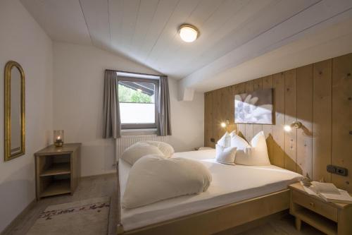 um quarto com uma cama grande com lençóis brancos e almofadas em Haus Alpin em Ellmau