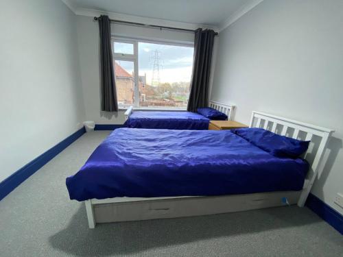 a bedroom with two beds with blue sheets and a window at 3 Room Apartment - Twinsdouble in Kings Lynn