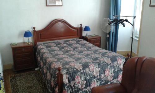リスボンにあるカーサ デ オスペデス ボア ノイテのベッドルーム1室(花柄のベッドカバー、椅子付)