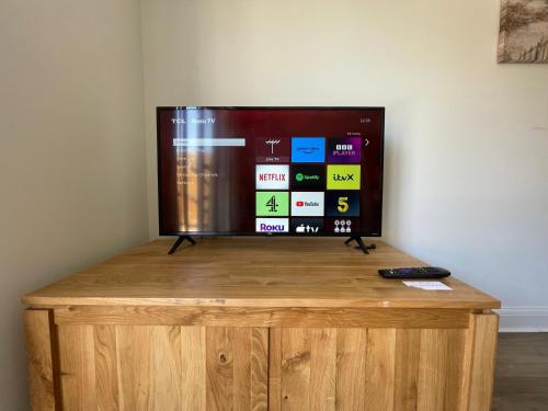 a flat screen tv sitting on top of a wooden stand at Barry Waterfront Stays - ENTIRE 3 BED PROPERTY in Barry