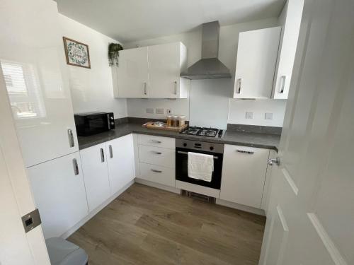 a kitchen with white cabinets and a stove top oven at Barry Waterfront Stays - ENTIRE 3 BED PROPERTY in Barry