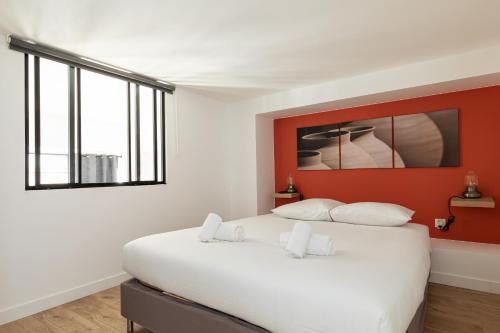 um quarto com uma grande cama branca e uma parede vermelha em DIFY Mazenod - Prefecture em Lyon