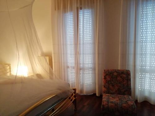 een slaapkamer met een bed, een stoel en gordijnen bij Sirolo - Pesciolino Azzurro in Sirolo
