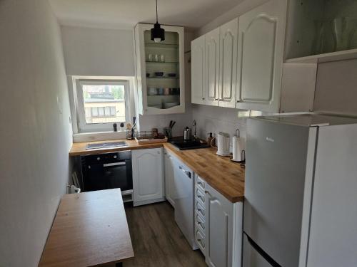 a kitchen with white cabinets and a white refrigerator at Little Wish in Gdańsk