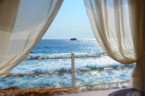 a window with a view of the ocean and a ship at Monte Carlo Sharm Resort & Spa in Sharm El Sheikh