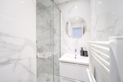 a white bathroom with a shower and a sink at Appart' Terrasse plein centre in La Ferté-Gaucher