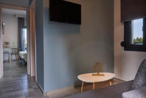 a living room with a table and a tv on a wall at Mirabilia Boutique Hotel in Kriopigi