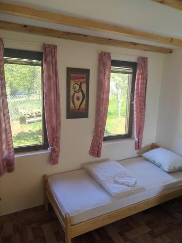 - un lit dans une chambre avec 2 fenêtres dans l'établissement Kuca u Vrdniku 2, à Vrdnik