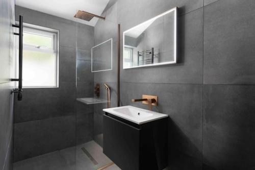 馬拉扎恩的住宿－Stunning new fully renovated flat in Marazion，一间带水槽、淋浴和镜子的浴室