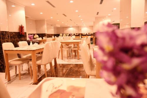 a restaurant with tables and white chairs and purple flowers at فندق الاندلس الماسى in Al Madinah