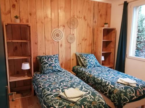 deux lits dans une chambre aux murs en bois dans l'établissement Maison en pleine nature, à Peyrilles