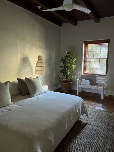 Un dormitorio con una gran cama blanca y una ventana en Hartebeeskraal Selfcatering cottage, en Paarl
