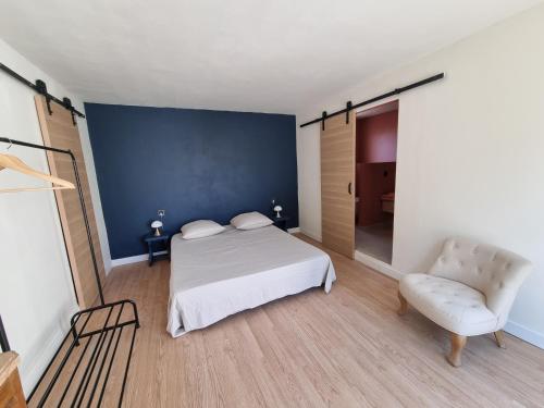 ein Schlafzimmer mit einem weißen Bett und einem Stuhl in der Unterkunft villa avec studio indépendant et piscine in Jonquières
