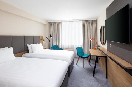 a hotel room with two beds and a desk and a tv at Holiday Inn Coventry M6, J2, an IHG Hotel in Coventry