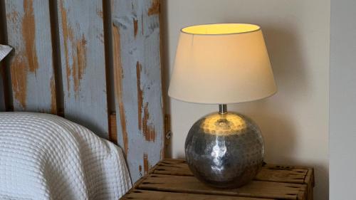 a lamp sitting on a table next to a bed at Les gîtes du Canal du midi - Gîte Bois & Cailloux in Montgaillard-Lauragais