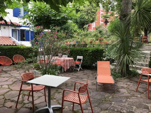 a table and chairs in a garden with a table and chairsktop at Hôtel Ohartzia in Saint-Jean-de-Luz