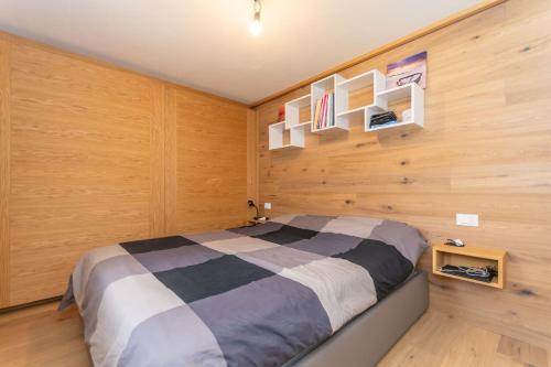 ein Schlafzimmer mit einem Bett in einer Holzwand in der Unterkunft Appartamenti Marangon in Falcade